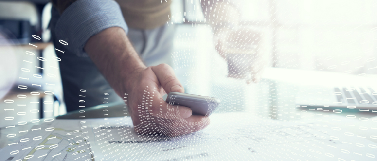 A photograph of a man holding a smartphone while standing at a desk. Overlaid on the photograph are arcs of binary numbers.