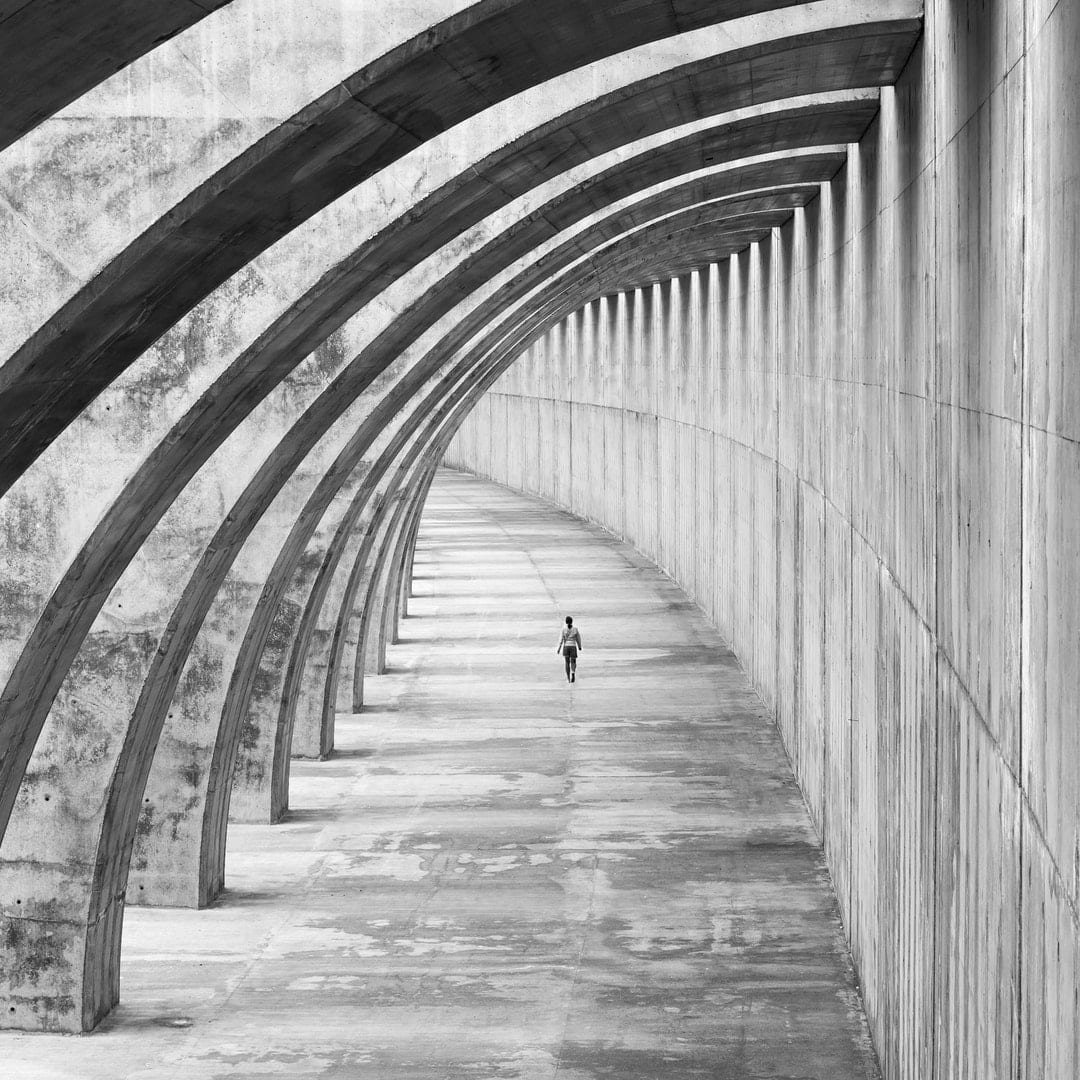 A person walks along an enclosed bridge.