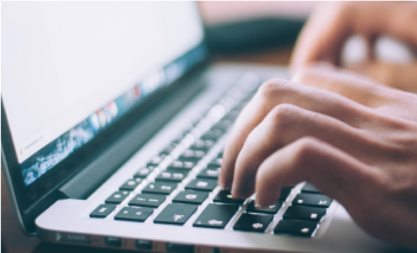 A close up of hands typing on a keyboard of a laptop.