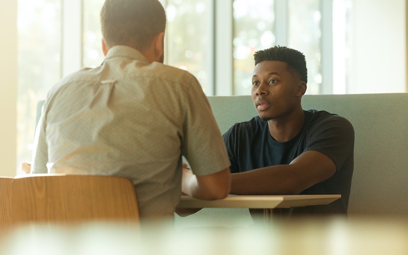 A photograph of two men sitting at a table, facing each other.
