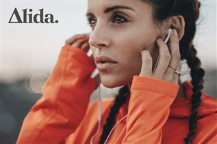 A photograph of a woman holding on to headphones in her ears. The photograph is labeled Alida.