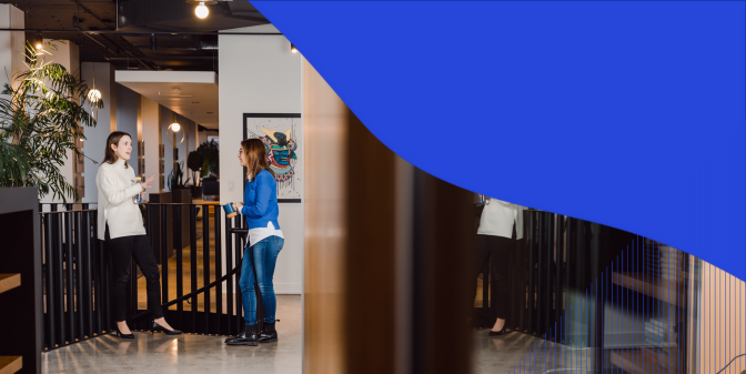 Two coworkers talking near the stairs railing with abstract graphic on the photo